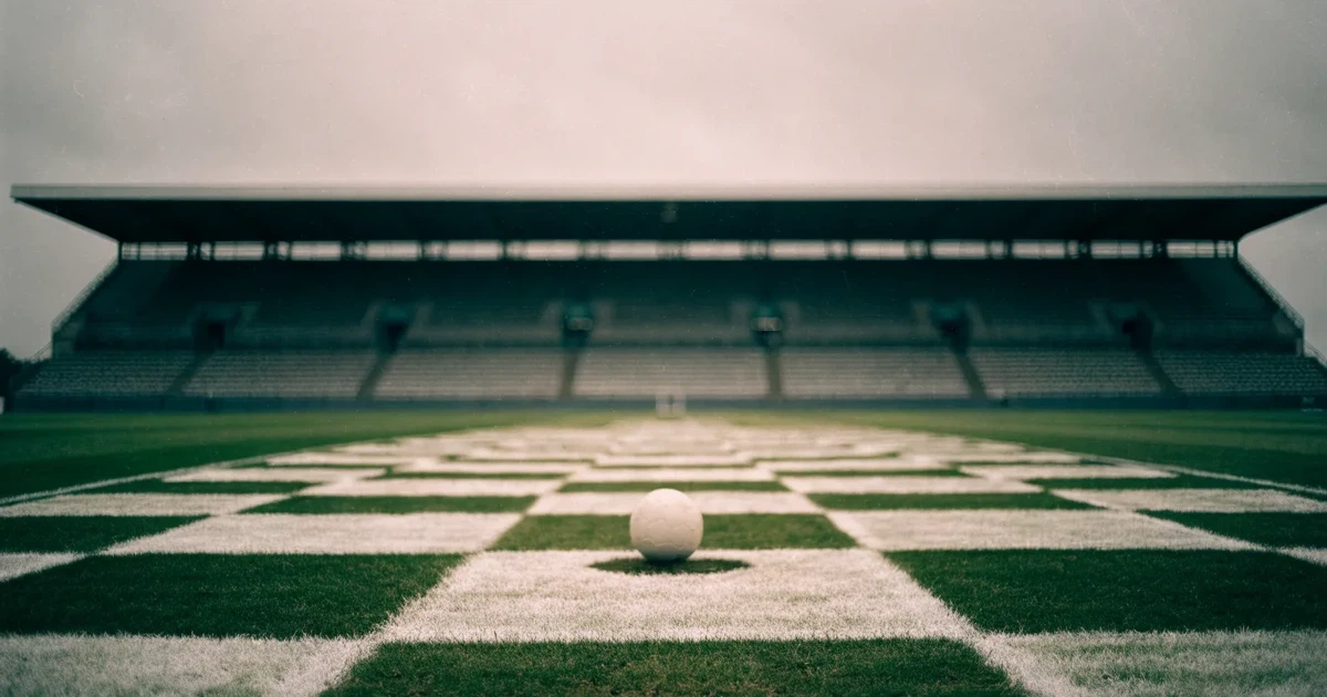 Ein Fussball liegt auf dem Anstosspunkt eines frisch gemähten Rasens, dahinter eine grosse Tribüne unter bewölktem Himmel